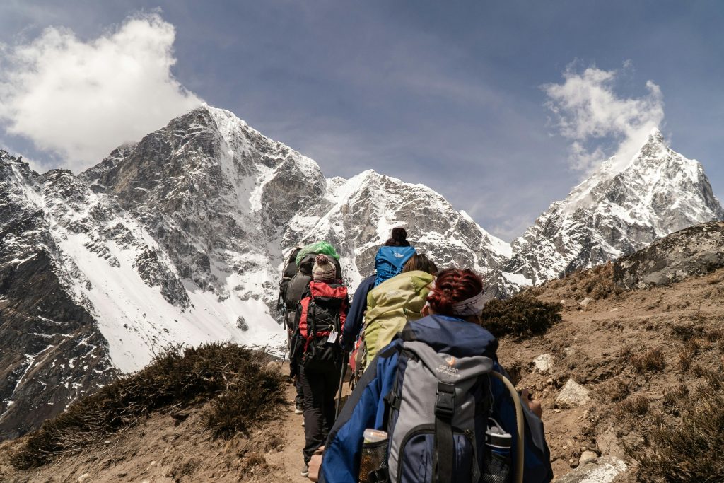 pexels-photo-2609459-2609459 Group of hikers trekking on a sunny day with snow-capped mountains in the background. Outdoor adventure scene.
