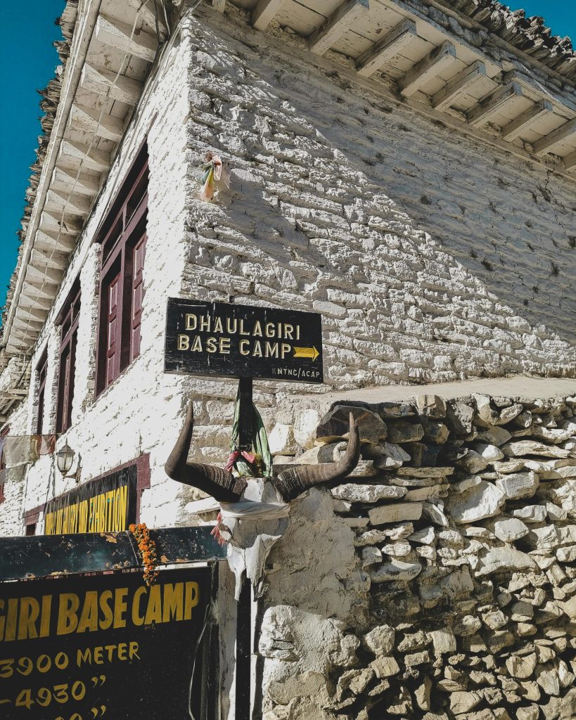 pexels-photo-34714282-34714282 Rustic sign and architecture mark the entrance to Dhaulagiri Base Camp in Nepal.